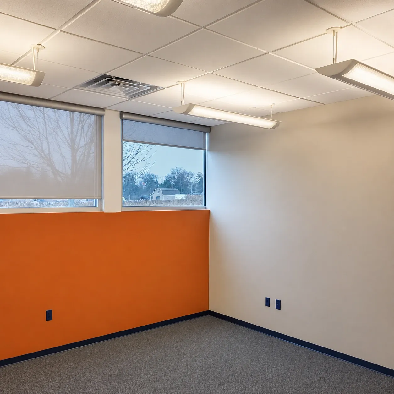 Commercial office with an orange accent wall, cream walls, and dark base trim