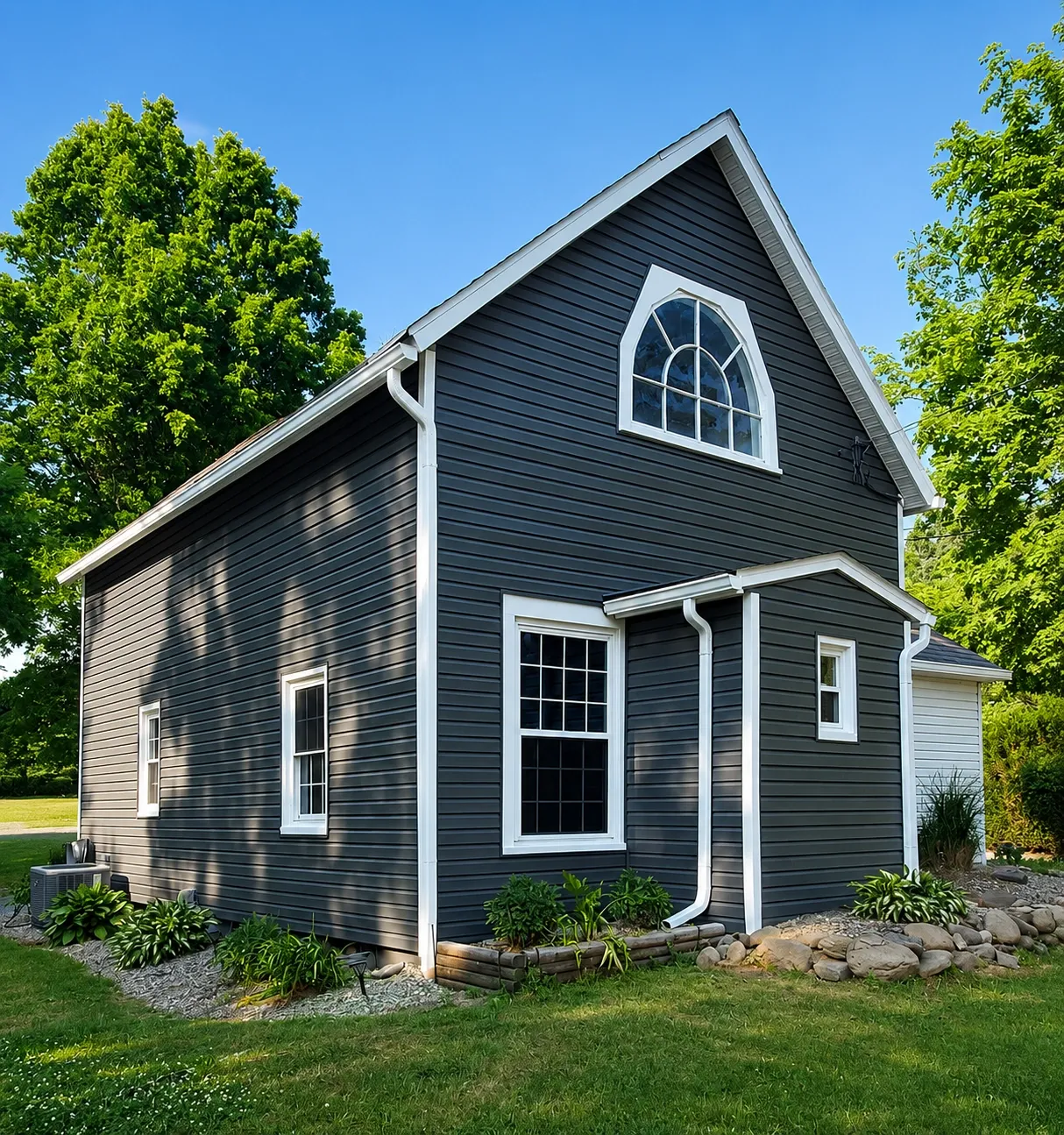 Completed dark gray house exterior with white window and roof trim