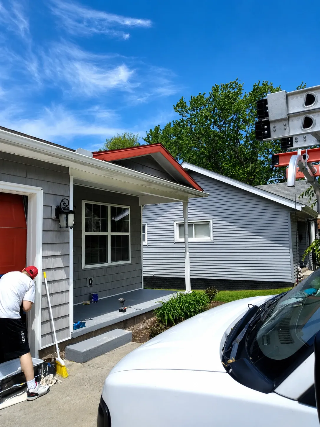 Gray home exterior with red fascia accent and a painted porch slab