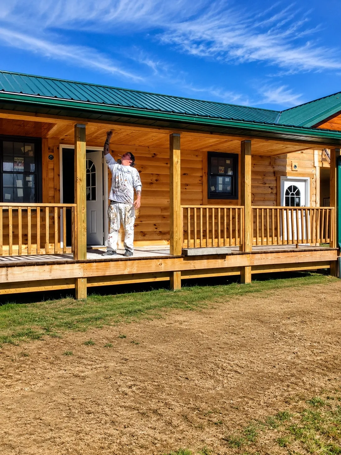 Log cabin exterior with green metal roof and covered porch