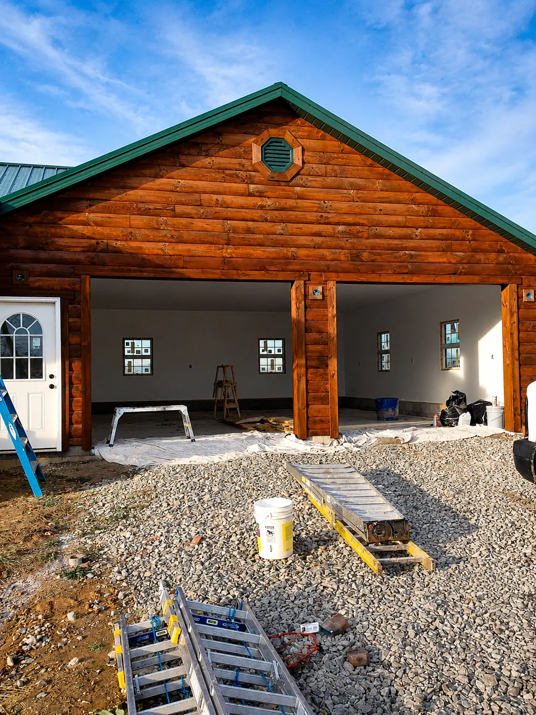 Log cabin exterior with freshly stained timber, green metal roof, and ladders