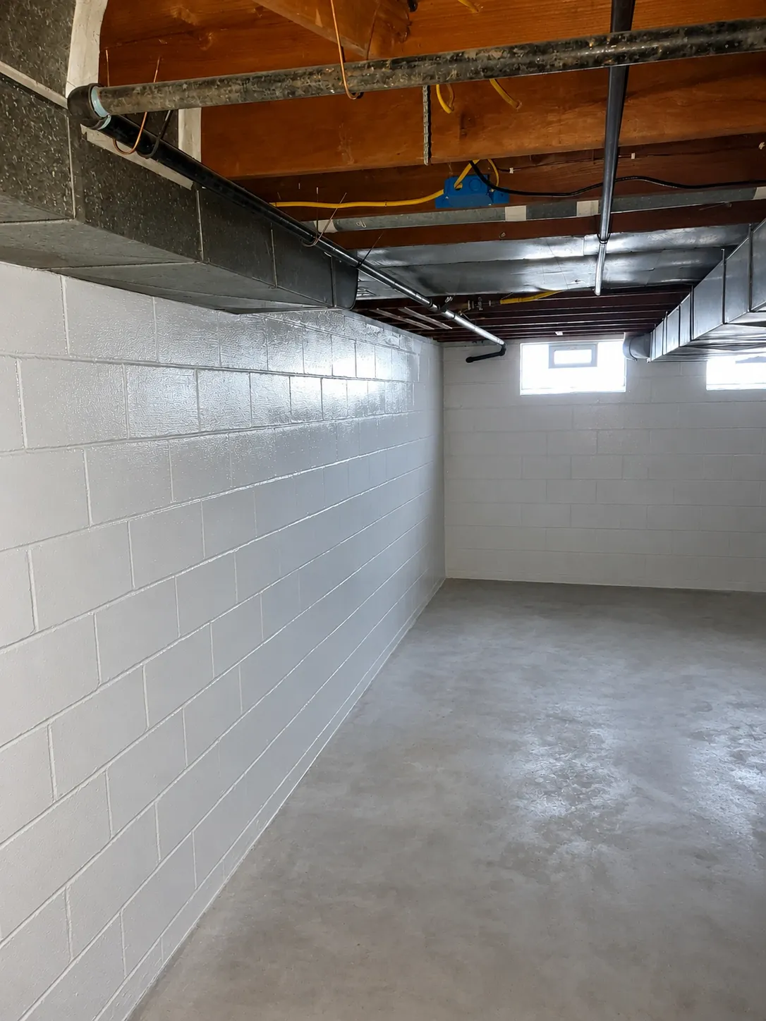 Freshly painted white block basement walls with exposed joists and ductwork