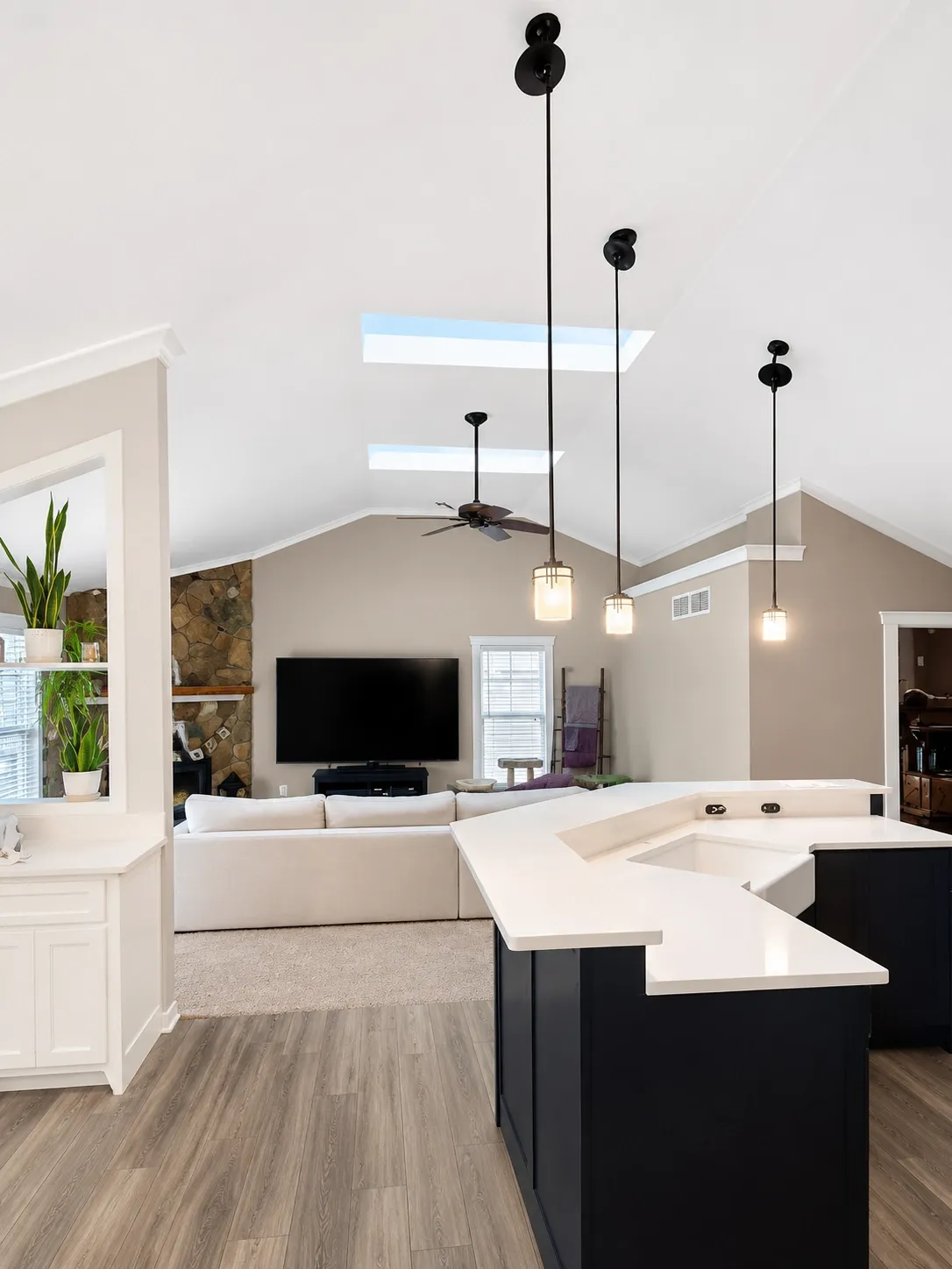 Finished open living space with vaulted white ceiling and a navy kitchen island