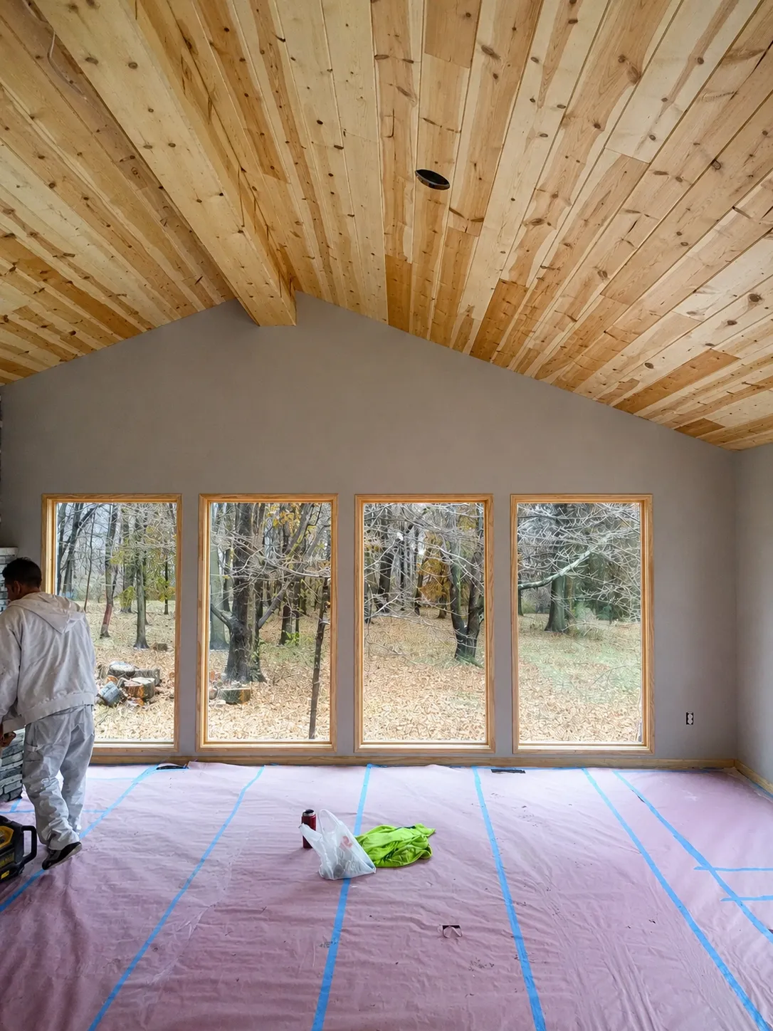 Painter preparing a vaulted room with wood plank ceiling and masked floor