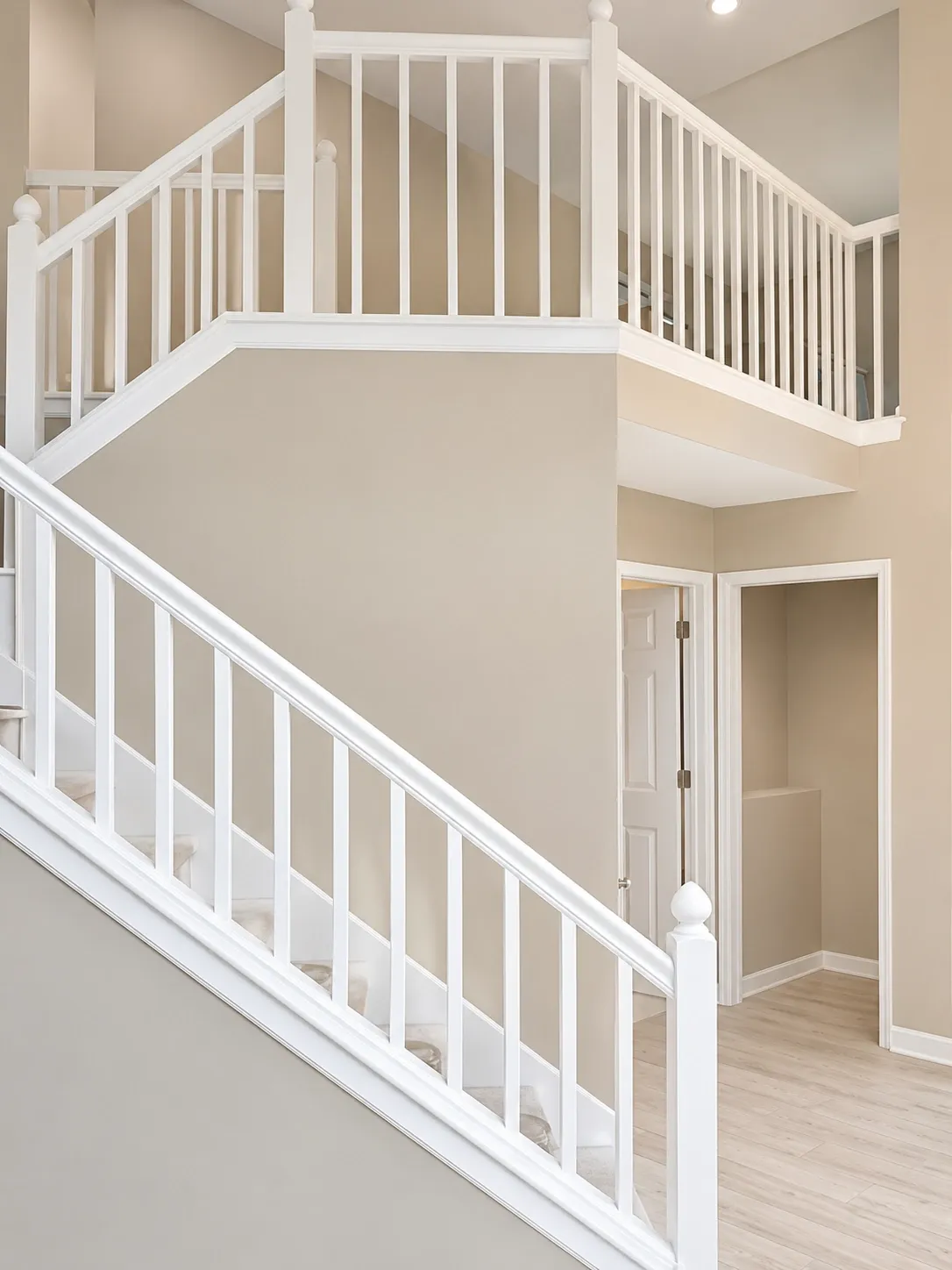 Finished stairwell with white painted railing, balusters, and neutral walls